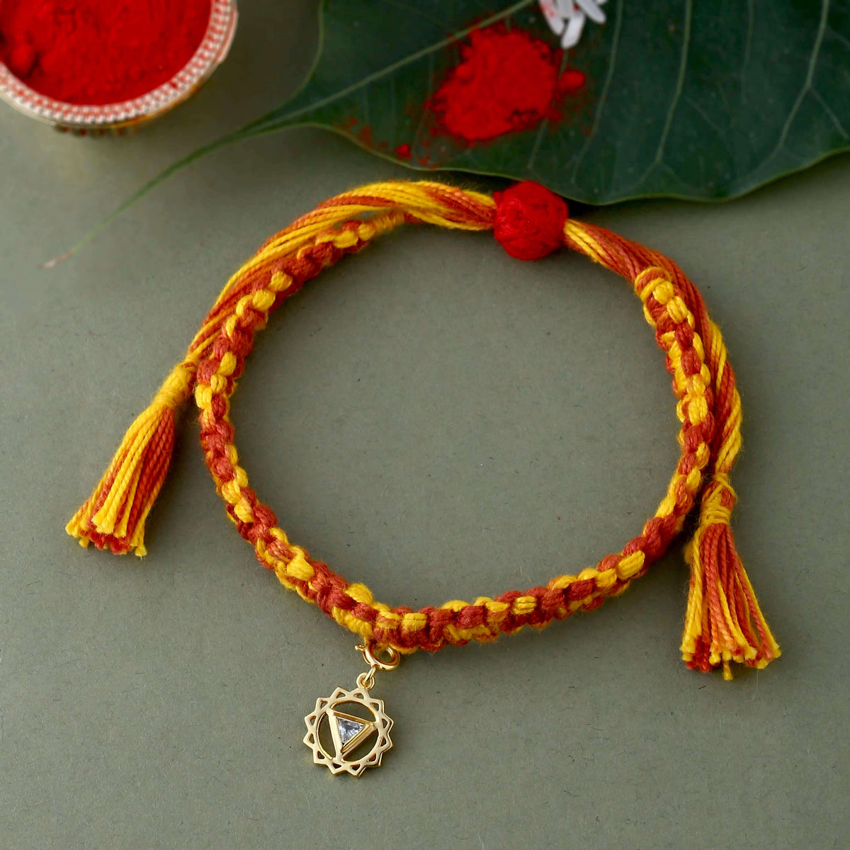 Gold Vishuddha chakra rakhi studded with Blue Topaz Gemstone