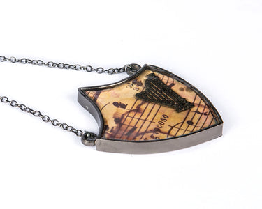 Shield neckpiece with musical instrument harp on musical notes 